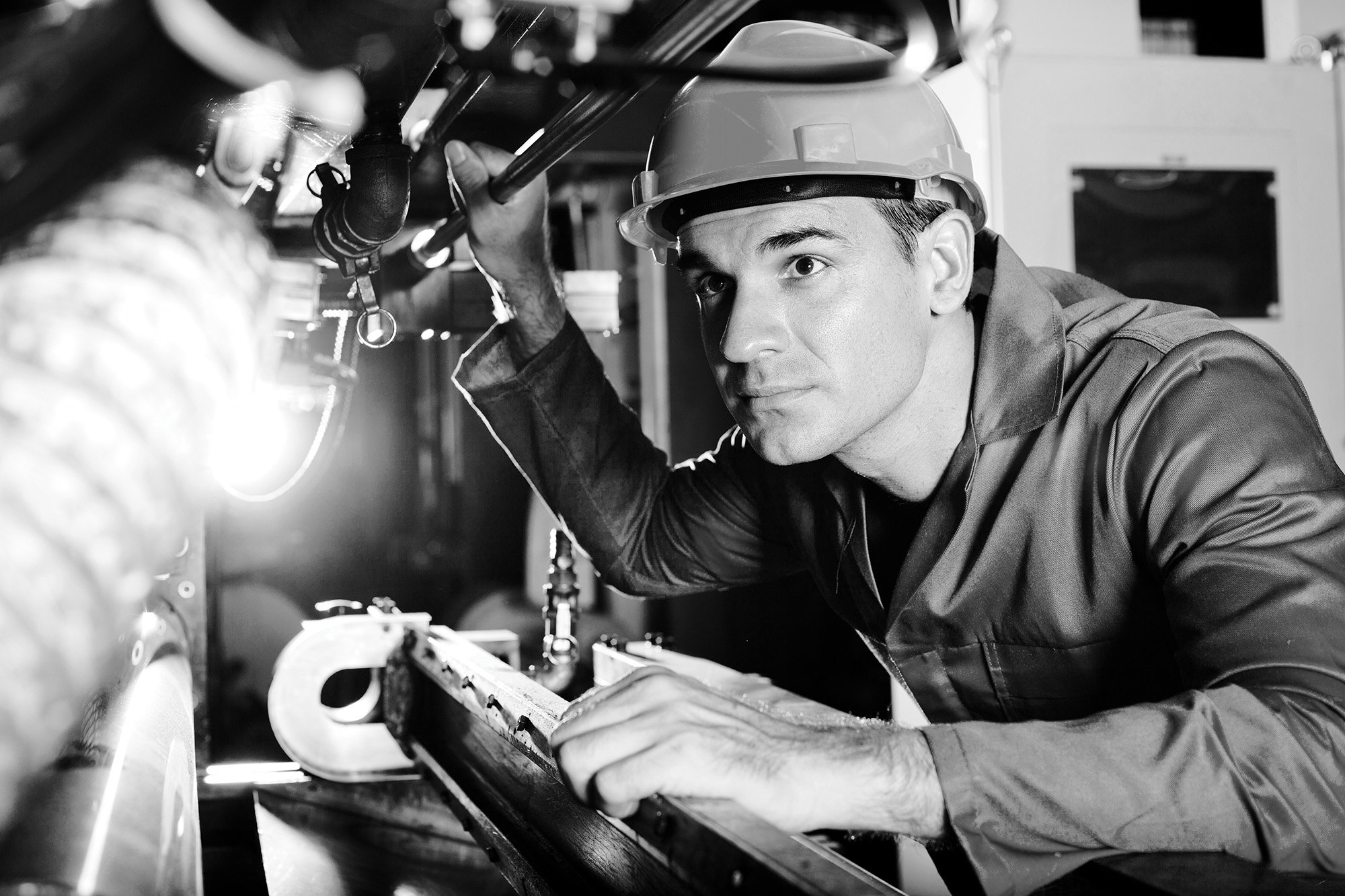 Operador industrial com capacete examinando equipamento em manutenção